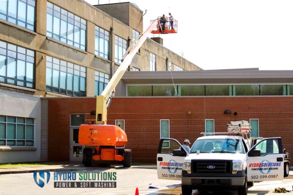 Hydro Solutions crew using a lift to clean the exterior of a school building.